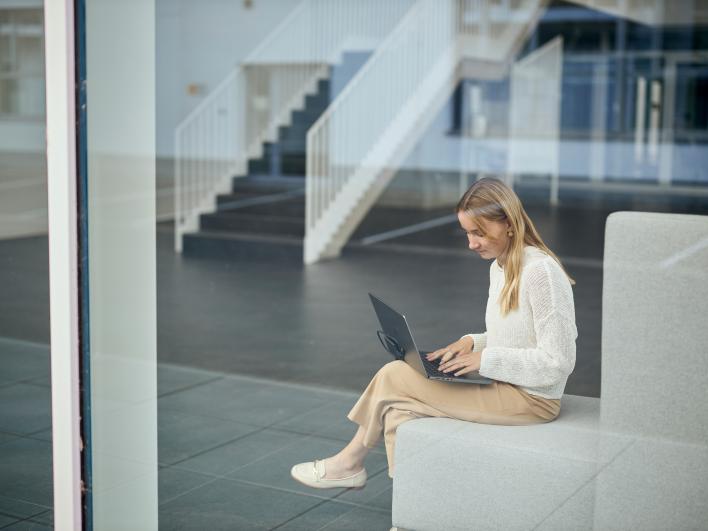 Mitarbeitende arbeitet am Laptop hinter einer Glaswand
